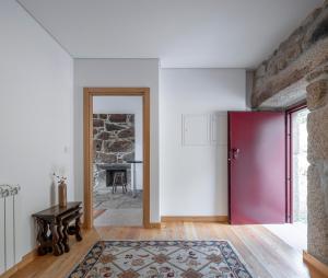 a room with a red door and a stone wall at Casa da Moiroa in Sendim