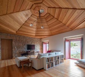 uma sala de estar com tectos de madeira e uma parede de pedra em Casa da Moiroa em Sendim