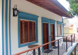 ein Haus mit blauen Fenstern und einem Balkon in der Unterkunft Pousada Perequê in Ilhabela