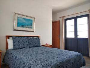a bedroom with a bed with a blue comforter and a door at Finca La Tabaiba Apartamento alto in Máguez