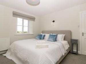 a white bed with blue pillows and a window at Somerset House in Bridgwater