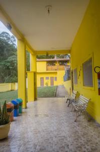 un edificio amarillo con bancos en un patio en Hostel Recanto da Serra, en Santo Antônio do Pinhal