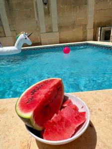 eine Schüssel Wassermelone auf einem Tisch neben einem Pool in der Unterkunft Birbuba House 2 in Għarb