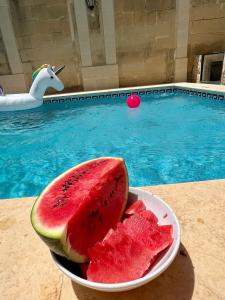 a bowl of watermelon on a table next to a pool at Birbuba House 2 in Għarb +7 photos