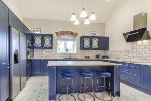 a kitchen with blue cabinets and a blue island with stools at The Dairy in Chesterfield