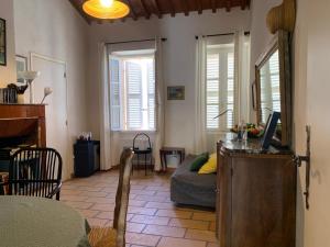 ein Wohnzimmer mit einem Schreibtisch, einem Sofa und Fenstern in der Unterkunft La Maison et son adorable jardin clos in Porquerolles