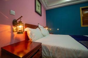 - une chambre avec un lit et une table avec une lampe dans l'établissement Mont Bleu Hôtel, à Assougoula Emo