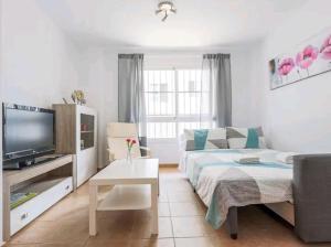 uma sala de estar com um sofá e uma televisão em Apartamento con patio y piscina cerca de Sevilla em La Algaba
