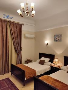 um quarto de hotel com duas camas e um lustre em Triomphe Hostel em Alexandria