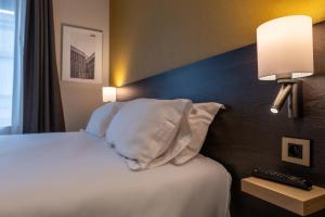 a hotel room with a bed with white sheets and pillows at Five Resort Cholet Centre in Cholet +34 photos