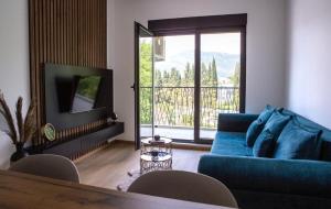 a living room with a blue couch and a large window at Apartment Lanterna in Tivat