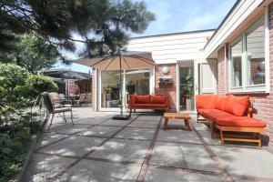 een patio met oranje stoelen en een parasol bij Sunnybeachhouse aan het bos, tussen zee en meer. in Noordwijkerhout
