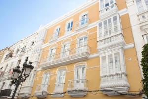 a yellow building with white windows and balconies at Apartamento Calle Nueva in Cádiz