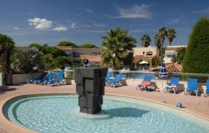 a pool with chairs and a fountain in the middle at Résidence haut de gamme - 45m2 refait à neuf en mai 2026 avec très grande piscine chauffée in Cap d'Agde