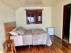 a bedroom with a bed and a window and a wooden floor at Central Chalés in Cambara do Sul