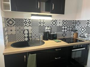 a kitchen counter with a sink and a tile wall at Appartement Evry in Évry-les-Châteaux