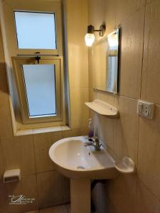 ein Bad mit einem Waschbecken, einem Spiegel und einem Fenster in der Unterkunft Triomphe Hostel in Alexandria