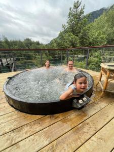 un grupo de personas en una bañera de hidromasaje en una terraza en Pucontours River Lodge, en Pucón