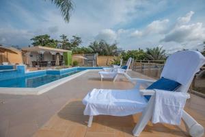 a pair of chairs sitting next to a swimming pool at Mont Bleu Hôtel in Assougoula Emo