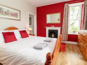 een slaapkamer met een groot bed met rode muren en een open haard bij How End in Braithwaite