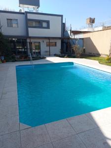 a blue swimming pool in front of a house at Don Trujo 2 - parque y pileta in Mendoza