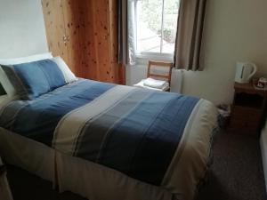 a bedroom with a large bed with a blue blanket at Beechlands B & B in Whitby