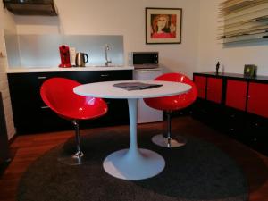 une cuisine avec une table blanche et deux chaises rouges dans l'établissement Studio's Park - Heverlee, à Louvain