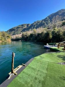 a boat is docked on a river next to a mountain at Pucontours River Lodge in Pucón