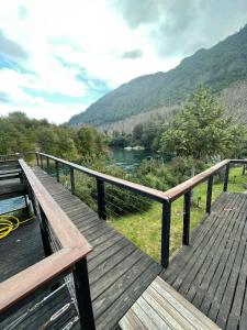 a wooden deck with a view of a river at Pucontours River Lodge in Pucón
