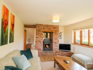 sala de estar con sofá y chimenea en Ellenhall Farm Cottage en Stafford