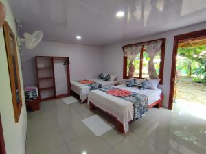 1 dormitorio con 2 camas y ventana en Cabañas Daneysha, en Tortuguero