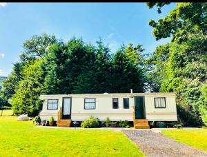 a caravan parked in a field with trees at CAYORETREAT STATIC CARAVAN in Longtown