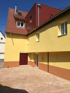 VoegtlinshoffenにあるGite du Meunierの赤い屋根の大きな黄色の建物