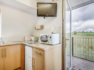 a kitchen with a microwave and a balcony at Glan Nug Bach in Betws-y-coed