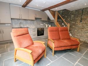 Duas cadeiras cor-de-laranja numa cozinha com uma escada em Fisherman's Cottage em Llandysul