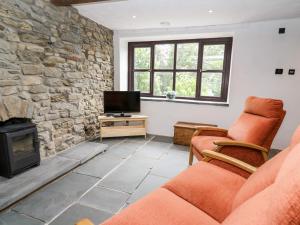uma sala de estar com uma lareira de pedra e uma televisão em Fisherman's Cottage em Llandysul