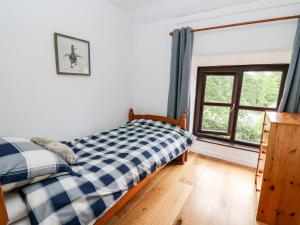 um quarto com uma cama e uma janela em Fisherman's Cottage em Llandysul