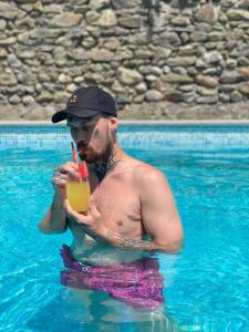 un hombre en una piscina bebiendo un trago en Hotel Villa Eniseli en Eniseli