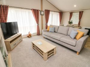 Una sala de estar con un sofá y un televisor en Barney's Retreat, en Carnforth