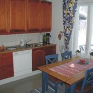 a kitchen with wooden cabinets and a table with chairs at Villa Nurminata in Parikkala