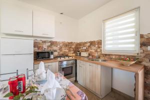 kuchnia z białymi szafkami, stołem i oknem w obiekcie Apartment Radeki Glavica 112b w mieście Loborika +7 zdjęć