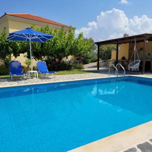 een zwembad met 2 stoelen en een parasol bij Villa Farangi in Gállos