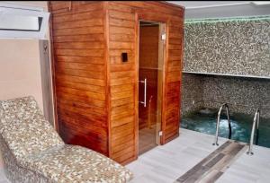 a bathroom with a shower and a chair and a tub at 3MMM Apartmani i Spa Centar in Obrenovac