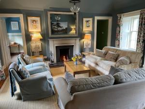 sala de estar con 2 sofás y chimenea en Neidpath Castle Cottage, en Peebles