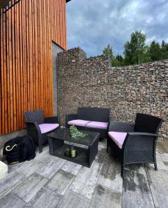 d'une terrasse avec des chaises, une table et un mur en briques. dans l'établissement Prima Apartmán Dolní Morava, à Dolní Morava