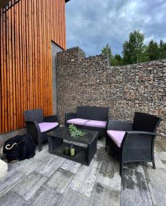 a patio with chairs and a table and a brick wall at Prima Apartmán Dolní Morava in Dolní Morava