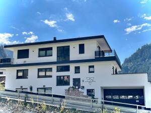 una casa blanca con ventanas negras y montañas al fondo en Alpenresidenz M Vermietungs KG, en See