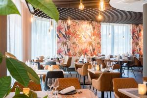 un restaurante con mesas, sillas y plantas en Best Western Hotel Airport Frankfurt en Frankfurt