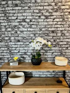 a wooden table with flowers on it in front of a brick wall at La Française - 85m2 in Vierzon