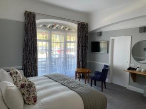 een slaapkamer met een bed, een tafel en een raam bij Bedford Hotel in Sidmouth